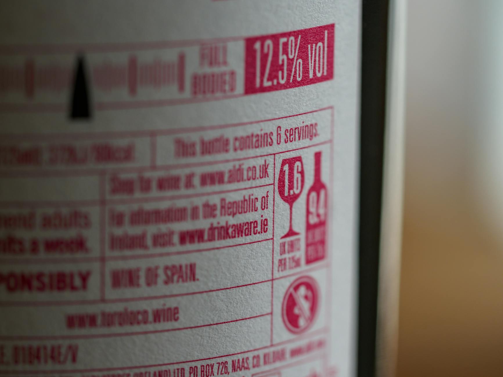 Close-up of wine label showing alcohol volume and health info.